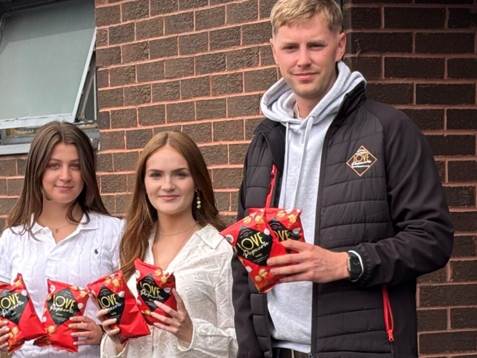 Two girls and a boy holding a bag of popcorn